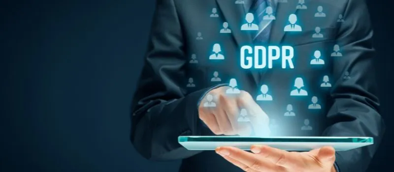 Executive holding a tablet with the word GDPR and people icons projected over his suit