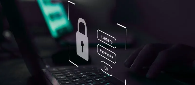 Padlock icon with username and password fields overlaid on a laptop screen in a dark setting