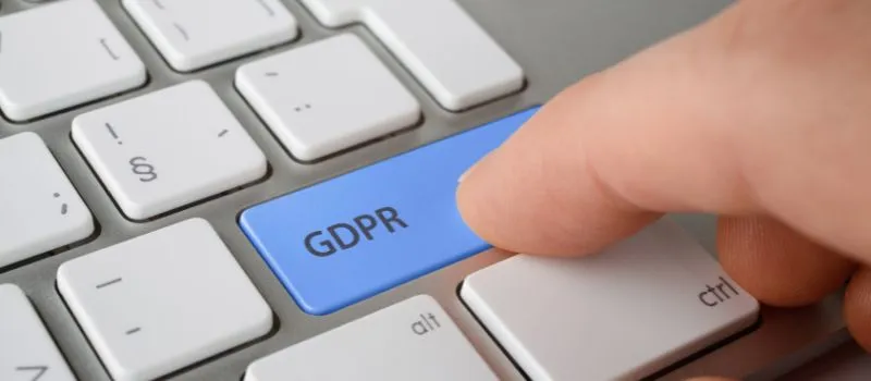 Dedo pulsando una tecla azul de teclado con el texto GDPR