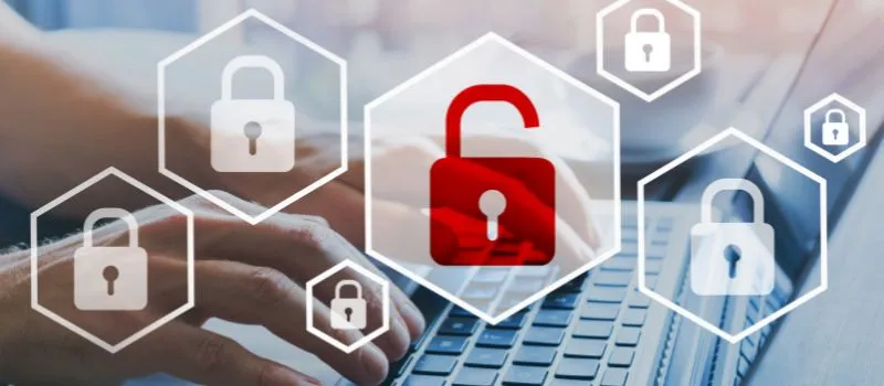 Hexágonos con iconos de candado de seguridad, uno de ellos rojo y abierto, sobre una persona usando un portátil